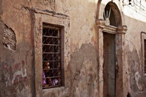 Uma menina olhando pela janela de sua casa em Bengasi, L&iacute;bia. Foto: UNSMIL